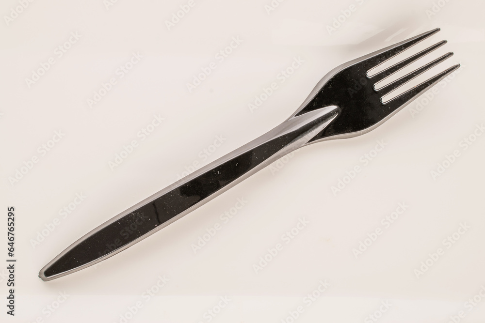 One plastic fork on a white ceramic plate, macro, top view. One plastic fork on a white ceramic plate, macro, top view.