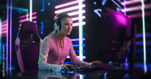 Portrait of a Happy Girl Focused on Playing an Online Video Game on a Desktop Computer. Stylish Streamer Playing Games with Internet Players in a Futuristic Neon Studio Room © Gorodenkoff