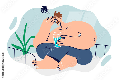 Man woke up from nightmare and sits on bed in bedroom with glass of water in hands