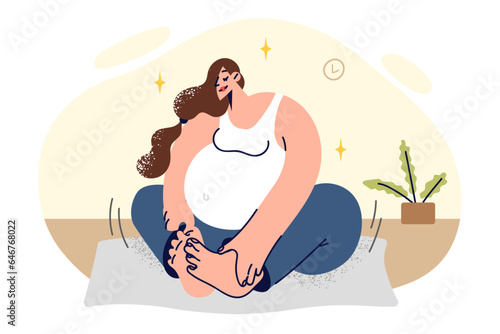 Pregnant woman doing morning exercises and stretching, sitting on floor on fitness mat