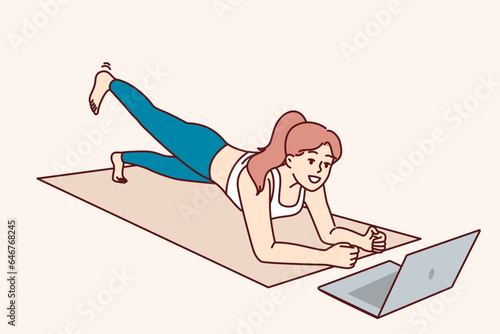 Woman is doing fitness lying on yoga mat and looking at laptop, listening to advice online trainer. Concept video lessons and distance training for athletes who want to do fitness without leaving home