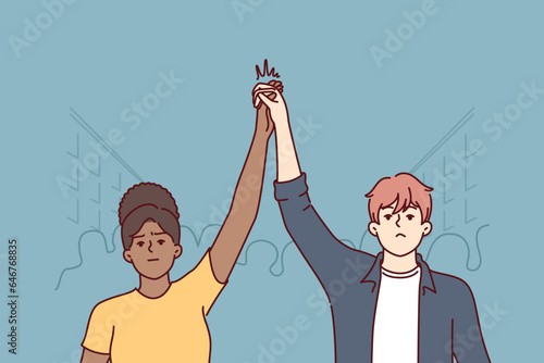 Protesting activists hold hands in solidarity, stand on street among crowd during revolution or uprising. Protesting multiracial man and woman participate in demonstration against discrimination