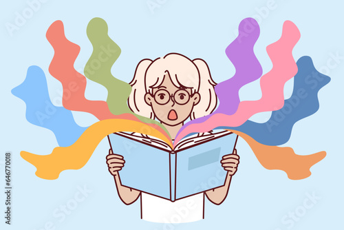 Surprised little girl reads book with exciting story and opens mouth in delight at plot. Shocked kid preteen holding open book with childrens fairy tales with unexpected characters