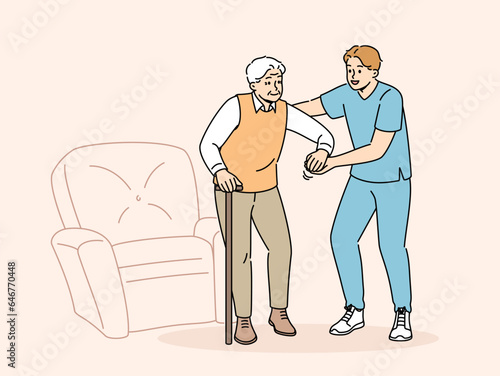 Medical worker helps sick pensioner get out of chair and walk around room or go outside. Providing assistance or support to pensioner after retirement and volunteer work in nursing home