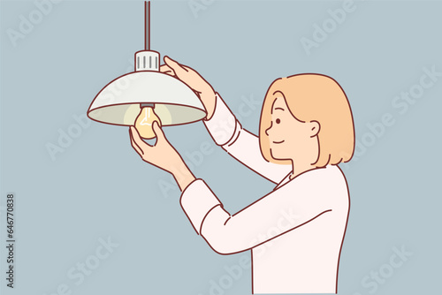 Woman independently changes burned-out light bulb in order to achieve high-quality lighting in house