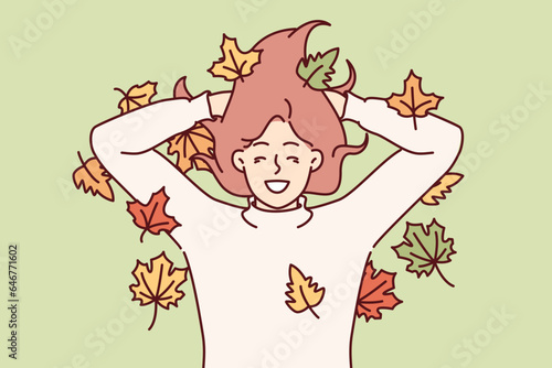 Woman lies in autumn park on ground among fallen multi-colored foliage and smiles rejoicing at onset of october. Girl enjoys autumn season and feels positive emotions from reunion with nature