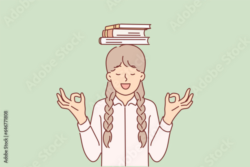 Schoolgirl is meditating standing with books on head and smiling making akasha mudra gesture