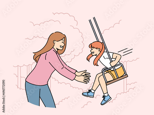Mom takes daughter on swing in park and enjoys relaxing with child in fresh air. Happy family of woman with little girl having good summer vacation or weekend in backyard with swing