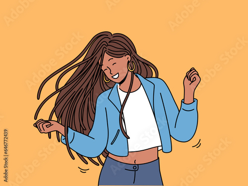 Dancing teenage girl enjoys rhythmic movements to music and swings long dreadlocks. Dancing ethnic woman in casual clothes, relaxing at disco or nightclub and dreams of becoming professional dancer