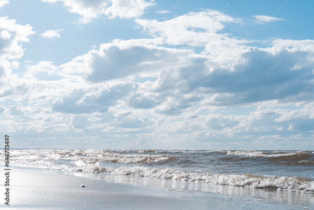 Wonderful view of clean beach seashore coastline, calm blue water, little sea waves, turquoise sky on sunny day. Summer.