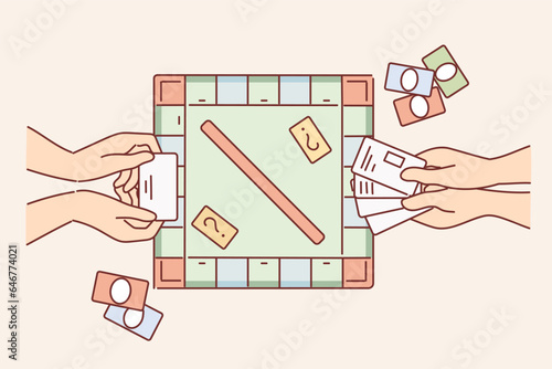 Hands of people playing monopoly and holding toy currency to make purchases in financial game