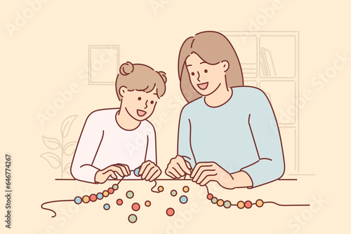 Mom and little daughter together make DIY bead bracelet to realize childs creativity