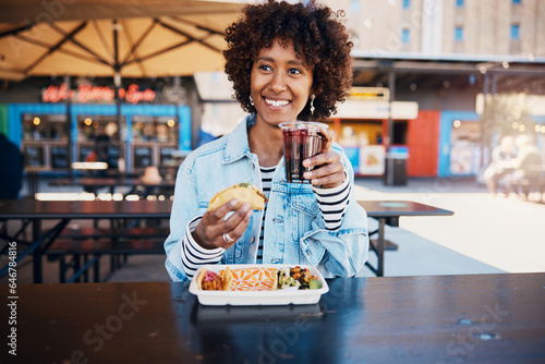 Smiling woman enjoying a drink with some tacos on a restaurant patio