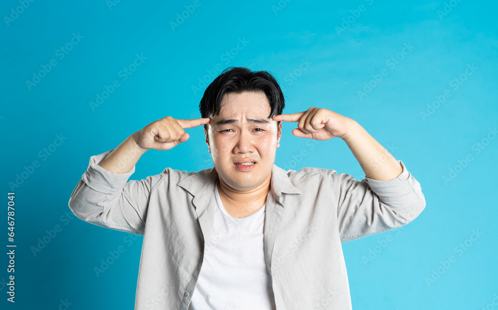 Image of Asian man having health problems, isolated on blue background Image of Asian man having health problems, isolated on blue background