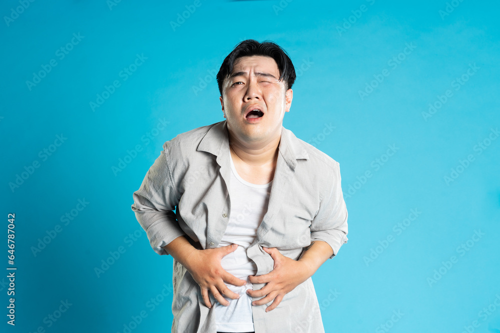 Image of Asian man having health problems, isolated on blue background Image of Asian man having health problems, isolated on blue background
