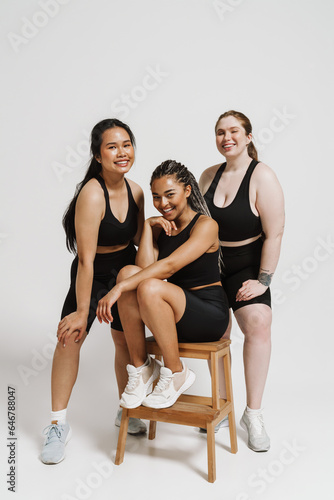 Portrait of three beautiful women with different body types posing together isolated over white background
