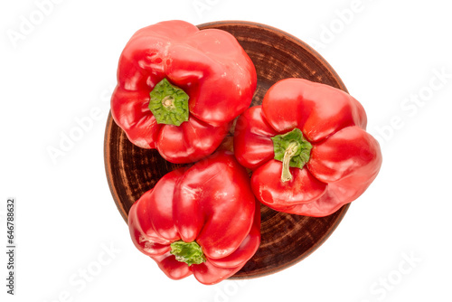 Three red sweet peppers on a clay plate on a white background  macro  top view.