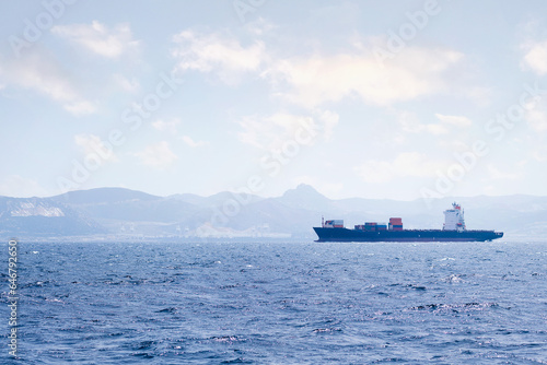 cargo ship sailing by the sea near the coast on a sunny day, concept of maritime transport of goods and import and export trade