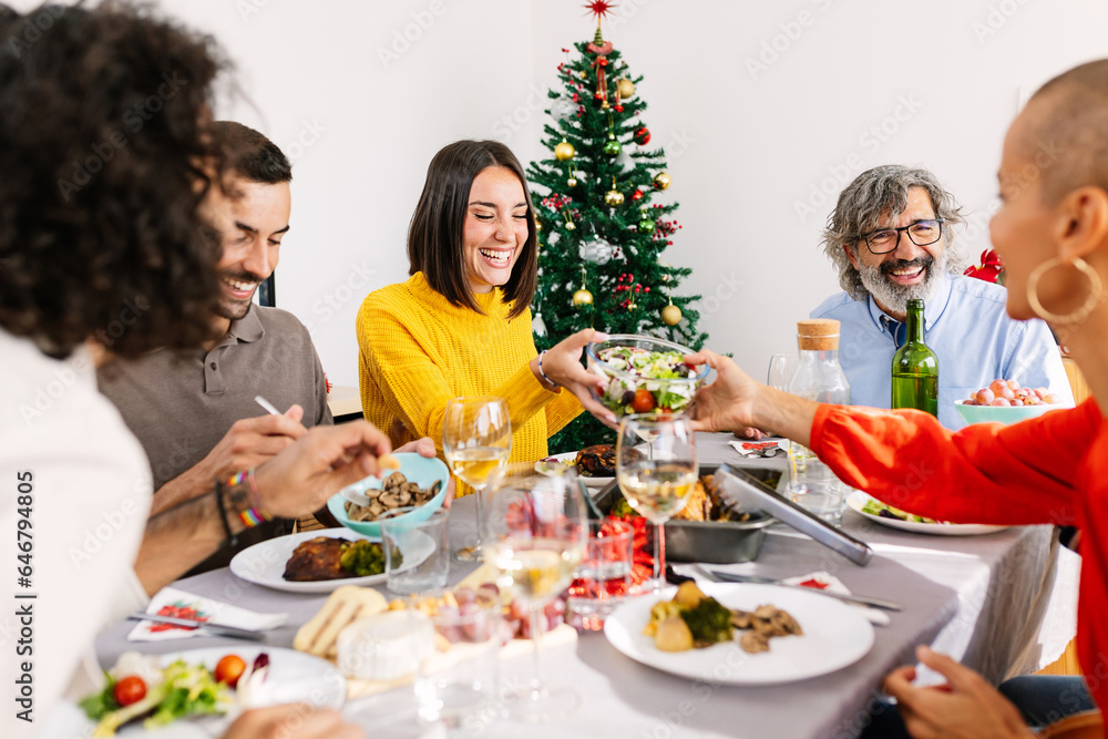 Happy multi generational family enjoying christmas dinner at home. Large group of diverse people having fun together celebrating xmas reunited around dinning table.
