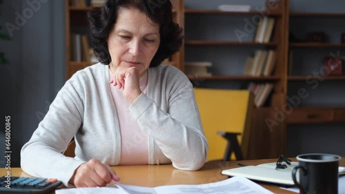 Sad tired disappointed older senior woman sitting with paper document. Unhappy mature grandmother experiencing stress managing bank finances calculating taxes planning loan debt pension payment