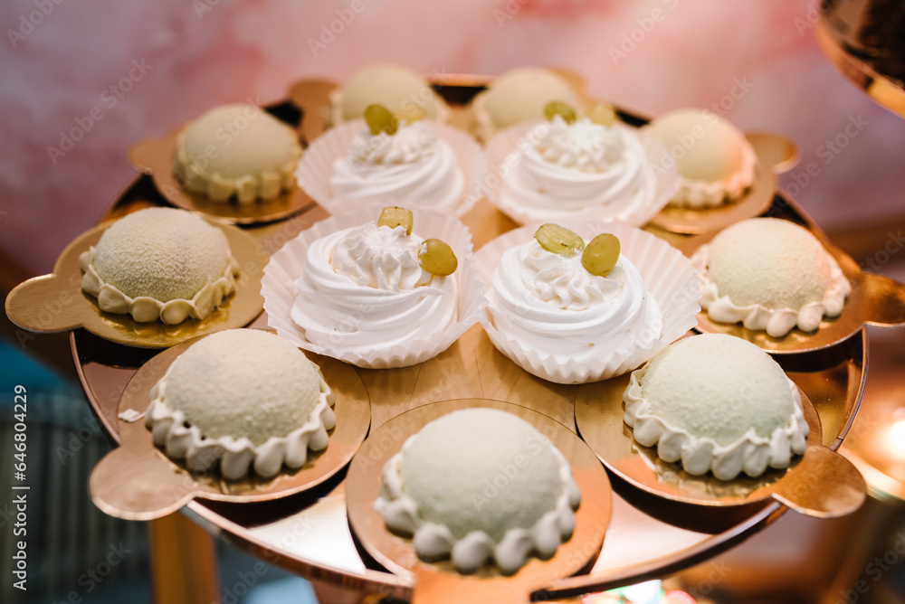 Sweet table. Plates of cakes and muffins. Table with sweets, buffet. Dessert table for party goodies for wedding. Decorated delicious. Candy bar with dessert for celebrating birthday, baptism. Closeup Sweet table. Plates of cakes and muffins. Table with sweets, buffet. Dessert table for party goodies for wedding. Decorated delicious. Candy bar with dessert for celebrating birthday, baptism. Closeup