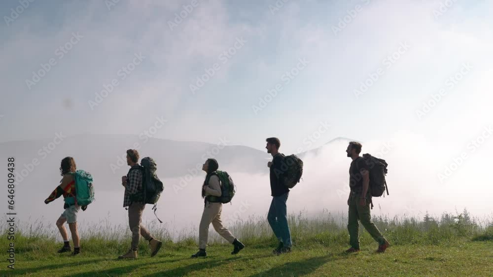 Handsome multinational friends hiking on the mountain with backpacks in the fog. Camping concept
