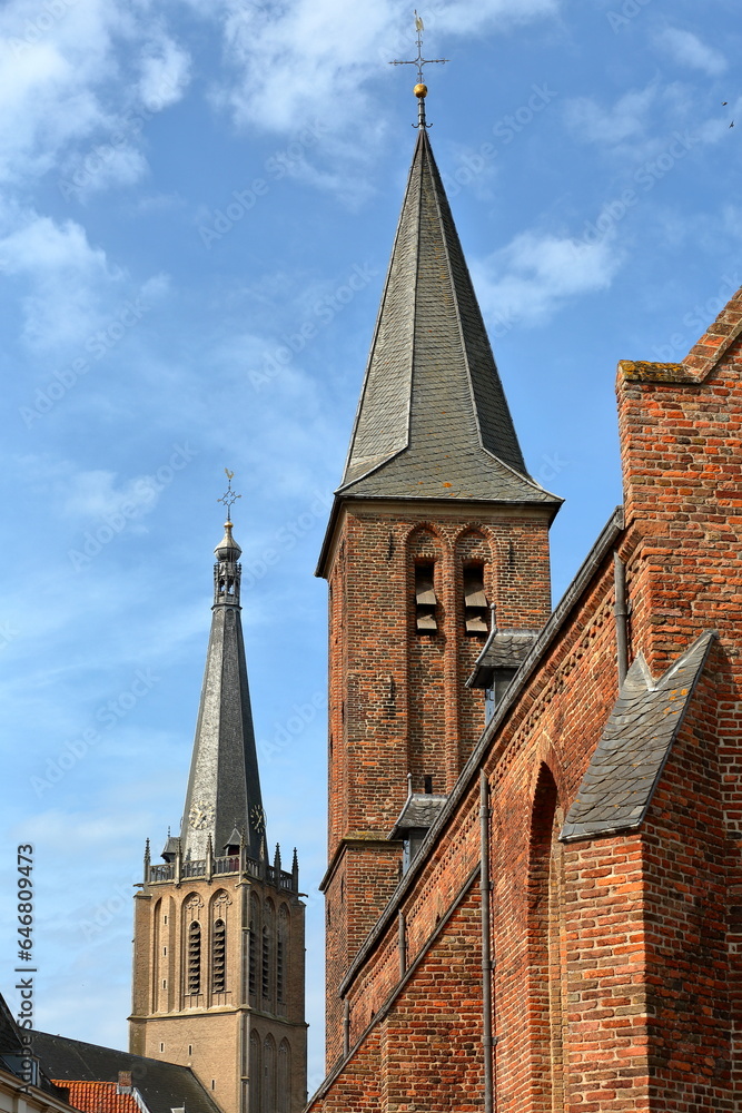 Close-up on the bell tower of Gasthuiskerk church in Doesburg, Gelderland, Netherlands, with the bell tower of Martinikerk church in the background on the left