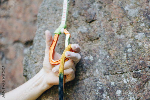 Close up of rock climber hand clipping rope in a quick draw caribener on rocky background photo