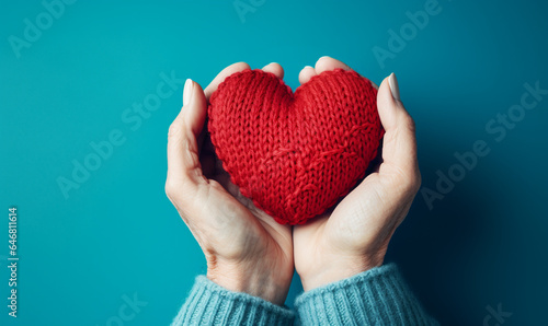 ein rotes gestricktes Herz in den Händen halten
