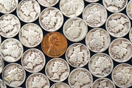 Abstract concept of individuality. A lone penny in a group of old mercury dimes.  American coins.