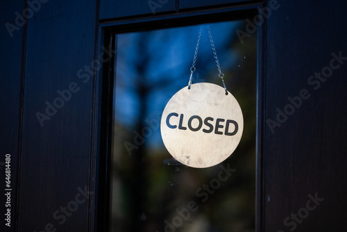 Closed sign hanging in glass pane of shop front door
