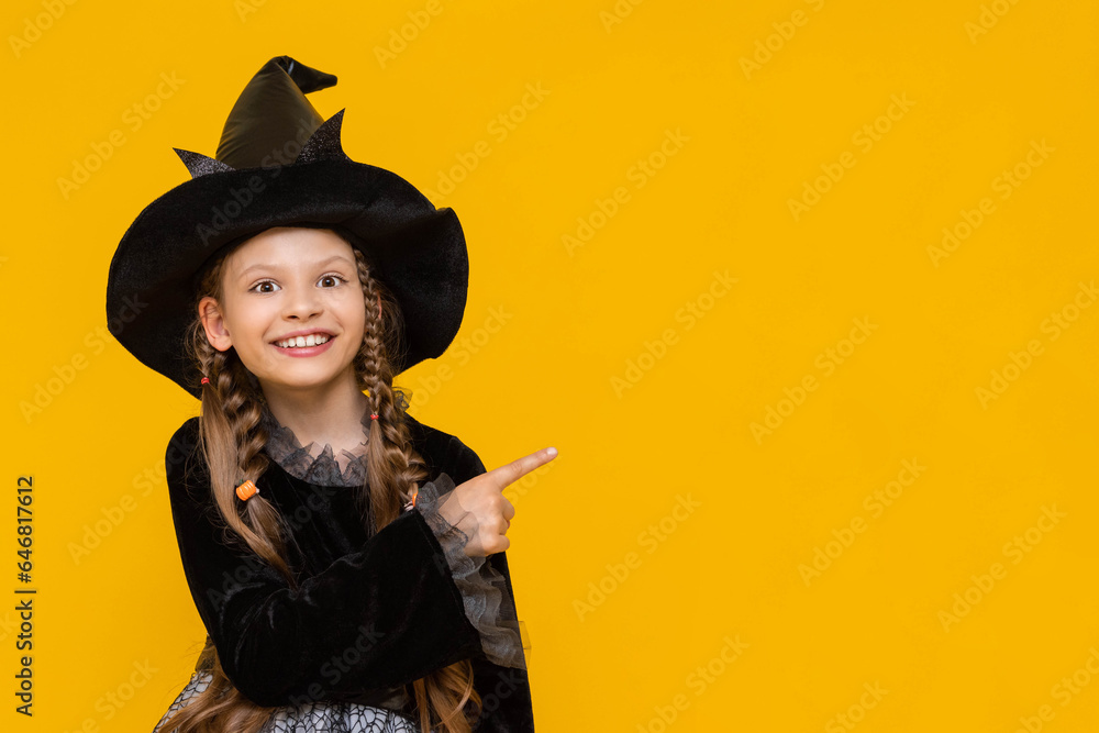 A surprised girl in a witch's fancy dress and with long pigtails points to the side at an advertisement, a place for advertising with a cute witch, a witch on a yellow isolated background. A surprised girl in a witch's fancy dress and with long pigtails points to the side at an advertisement, a place for advertising with a cute witch, a witch on a yellow isolated background.