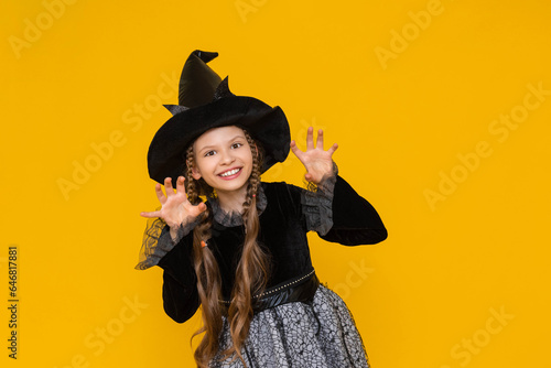 A young girl in a witch costume for Halloween is very angry and frightening, the evil little witch is very unhappy and bared her teeth.