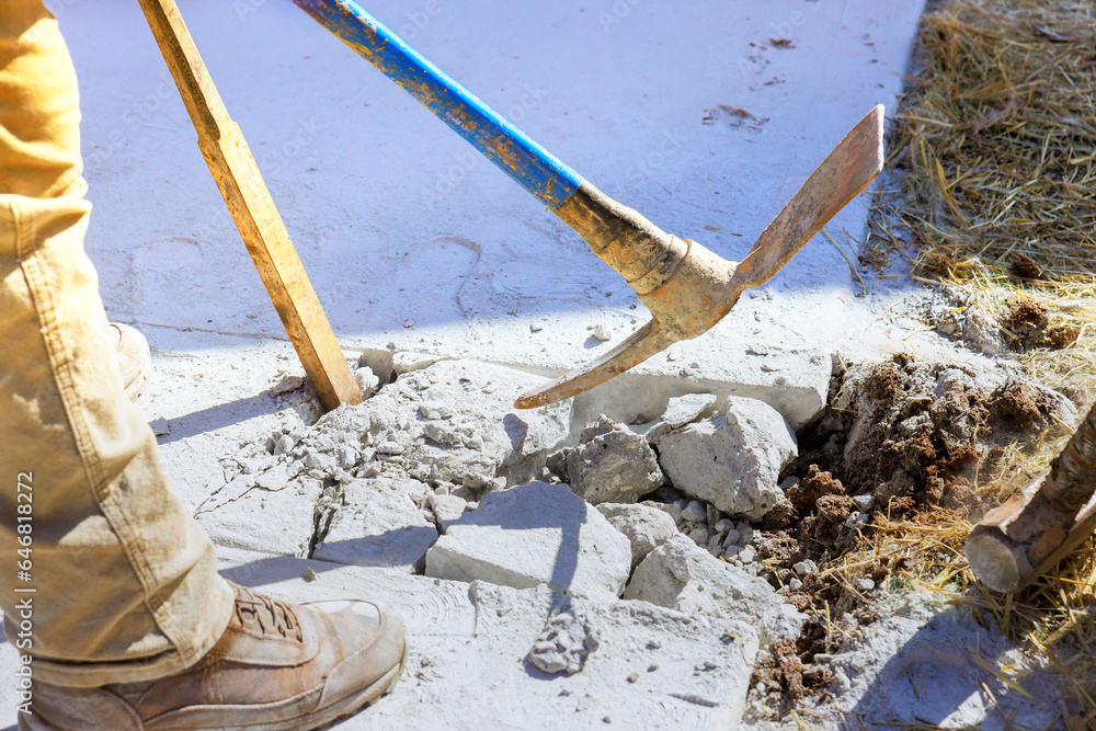 Pickaxe wielding worker smashes concrete old driveway on construction