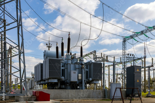 Three-phase high-voltage transformer of high electrical power at a substation against the blue sky.