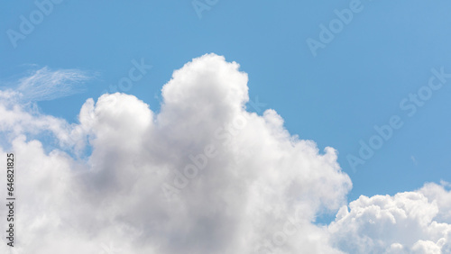 Panoramic background of blue sky with white clouds illuminated by it giving it a great volume. Cotton clouds over the clear sky. White clouds