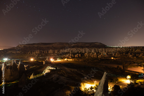 Night shot of the valleys of Cappadocia, from Goreme, Turkey. The longexposure photo show the stars, the towering mountain over the rocks, and the Red Valley.