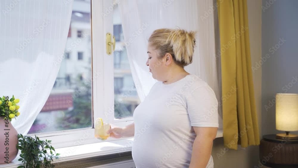 Obesity woman drinking diet beverage in front of window. Obesity woman drinking diet beverage in front of window.