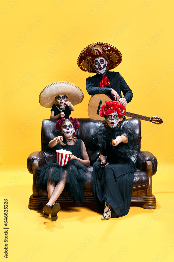 Halloween Family. Surprised father, mother and children in halloween skeleton spooky makeup watching films with pop corn.