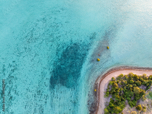 High angle aerial bird's eye drone view of a small beach section of Haman Island, a holiday resort islet with shallow, turquoise water - Whitsunday Islands, Great Barrier Reef, Queensland, Australia.