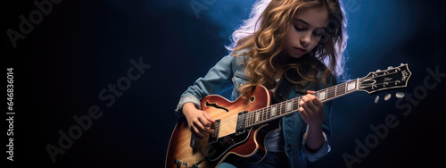 Teenage girl playing guitar on dark background