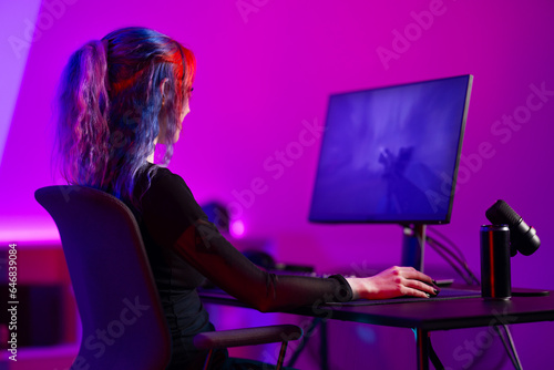 Fotografie Focused professional e-sport gamer girl streaming and plays first-person shooter