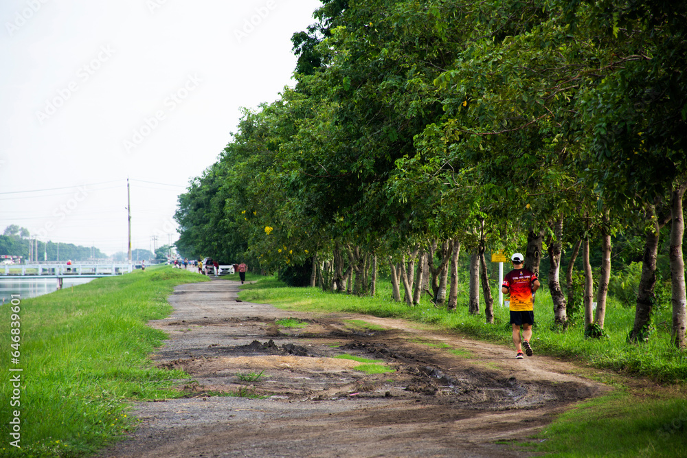 Asian thai people training jogging and exercise on rural street in morning time beside irrigation canal for running competition at countryside Sai Noi city on August 27, 2023 in Nonthaburi, Thailand