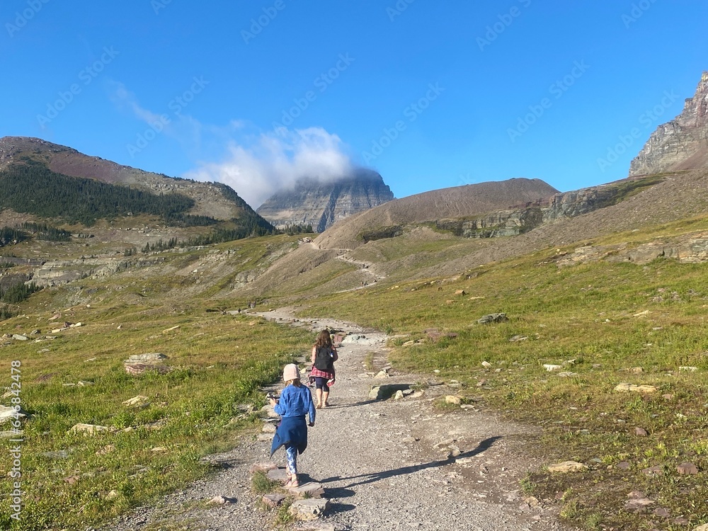 A beautiful photo of a mom and daughter hiking the landscape of Hidden Lake trail in Glacier National Park