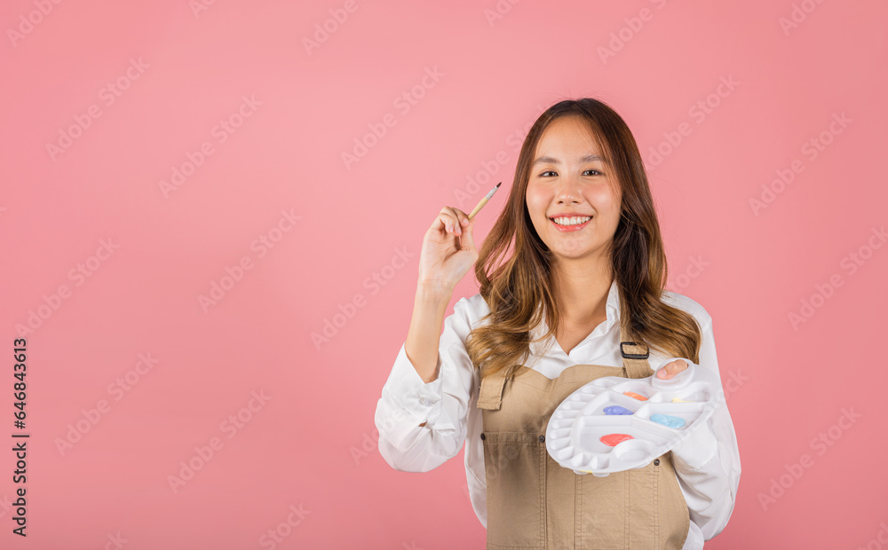 Asian beautiful young woman artist holding brush and paint palette, Happy female painting using paintbrush and palette with colors, studio shot isolated on pink background, Paintings and art equipment Asian beautiful young woman artist holding brush and paint palette, Happy female painting using paintbrush and palette with colors, studio shot isolated on pink background, Paintings and art equipment
