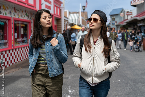 traveling lifestyle and people on vacation in usa. two leisure asian female tourists looking around surroundings as they walk the on busy street of Old Fisherman's Wharf in California © PR Image Factory