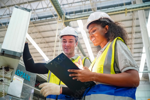 Industrial worker indoors in factory. Young technician with orange hard hat. Smart Caucasian factory worker wearing hardhat and working in power plant.