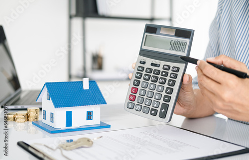Buying and selling houses and real estate prices. Concept. Man using calculator to count rent money.