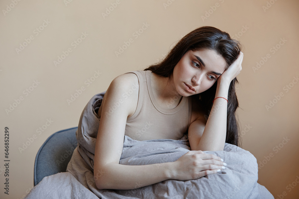 Minimal portrait of depressed young woman wrapped in blanket and struggling with mental health, copy space Minimal portrait of depressed young woman wrapped in blanket and struggling with mental health, copy space