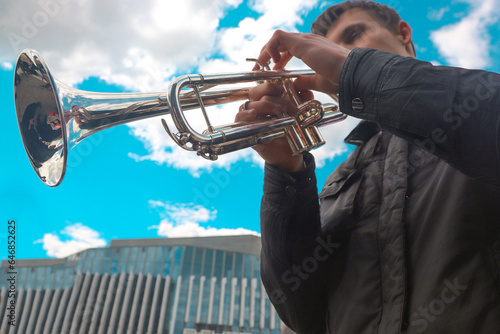 close-up of the hands of a street musician holding a gold-colored pump-action trumpet
